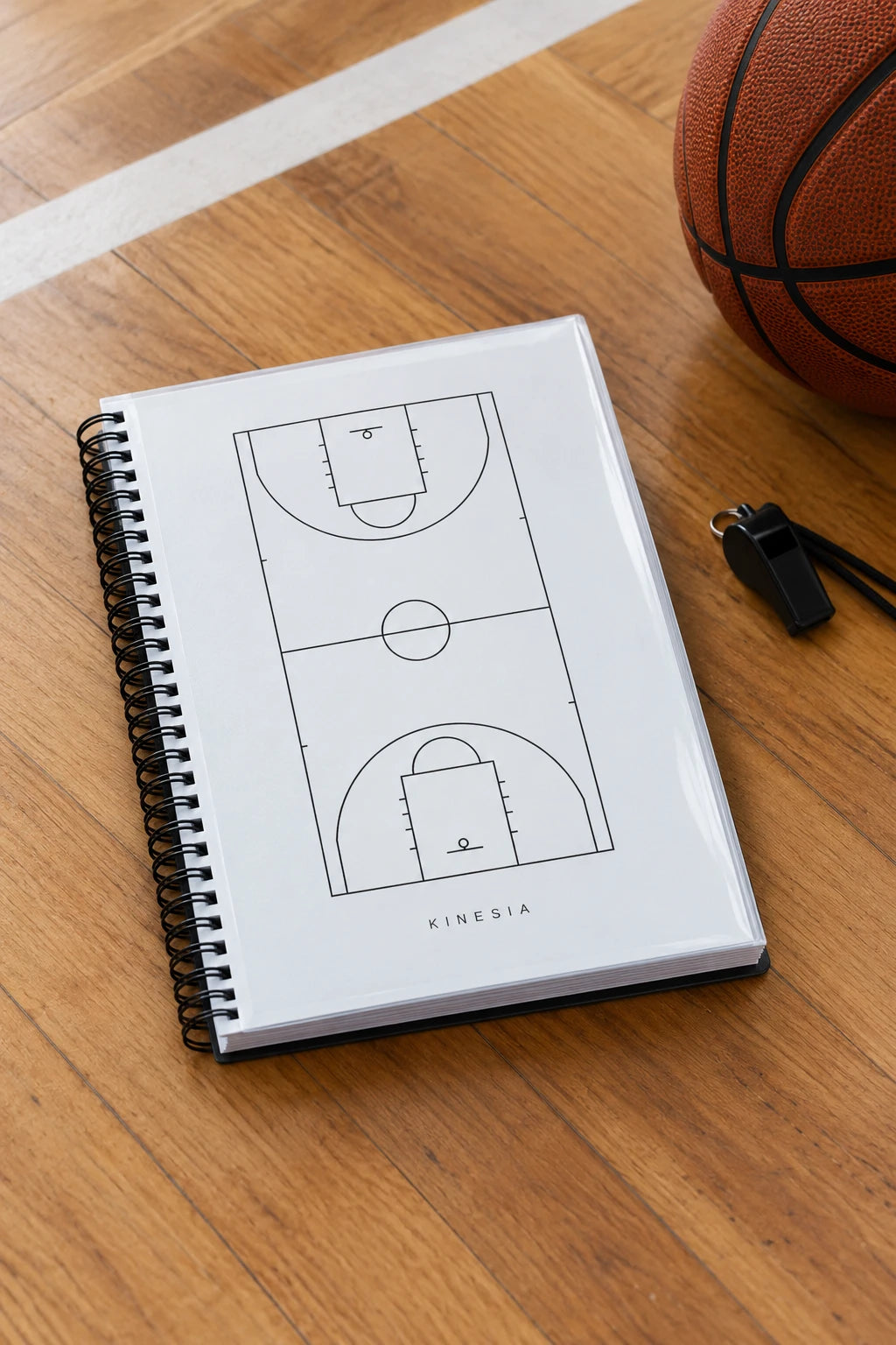 Libreta del entrenador Kinesia sobre el parqué de una cancha